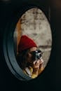 A woman in a red beanie photographs indoors with a vintage camera.